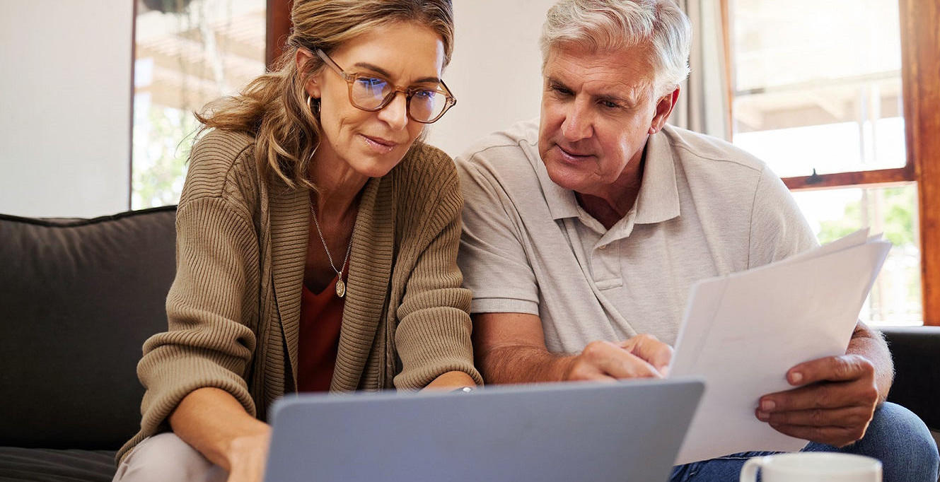 Para w średnim wieku sprawdza dokumenty na laptopie